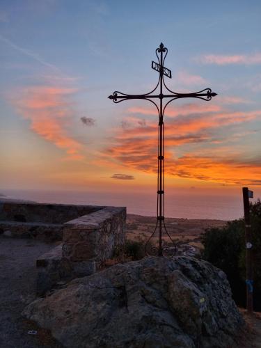 une croix au sommet d'un rocher avec le coucher du soleil dans l'établissement The Cosy Home Corbara by 1722, à Corbara