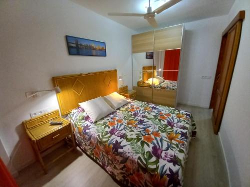 1 dormitorio con cama, mesita de noche y espejo en alojamientosmomi3, en Corralejo