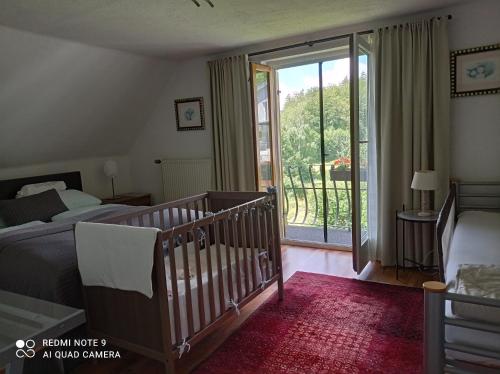 1 dormitorio con cuna, cama y balcón en Ferienhaus Familie Zimmermann en Keutschach am See