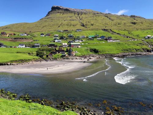 a view of a beach with a mountain in the background at Cosy apartment in Kvívík