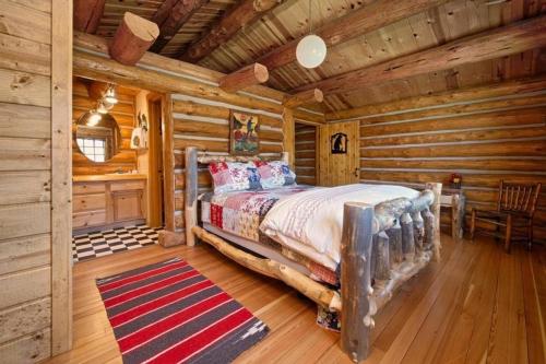 um quarto com uma cama num chalé de madeira em JHRL - Macker's Cabin, Amazing Log Cabin, Sleeps 16 em Wilson