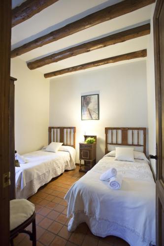 two beds in a room with white sheets at Mas Pratsevall in Taradell