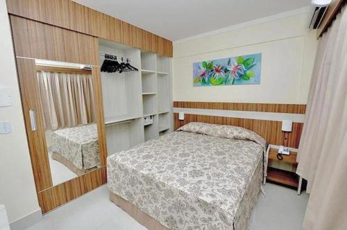 małą sypialnię z łóżkiem i lustrem w obiekcie L'acqua diroma I, II, III, IV e V- Aptos w mieście Caldas Novas