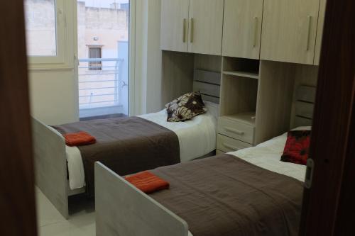 ein kleines Zimmer mit 2 Betten und einem Fenster in der Unterkunft Sunset and Seaview Apartment -Brand New in Mellieħa