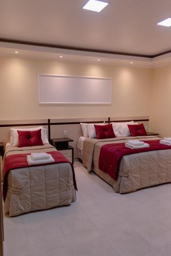 two beds with red pillows in a room at HAUER HOTEL in San Vicente