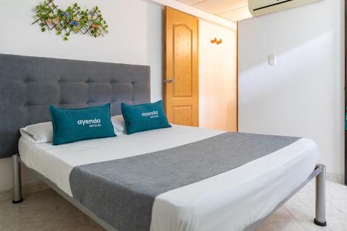 a bedroom with a bed with two blue pillows at Hotel Ayenda Guadalupe in Neiva