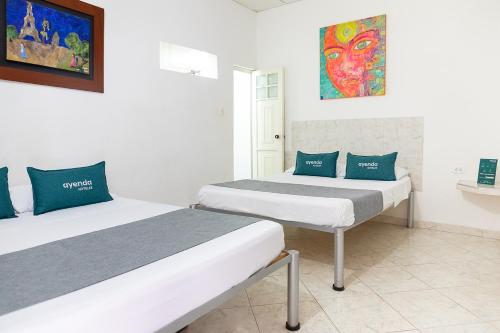 ネイバにあるHotel Ayenda Guadalupeのベッド2台が備わる客室で、壁には絵画が飾られています。