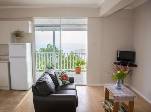 Morne SeaView Apartments في كاستريس: غرفة معيشة مع أريكة سوداء ومطبخ