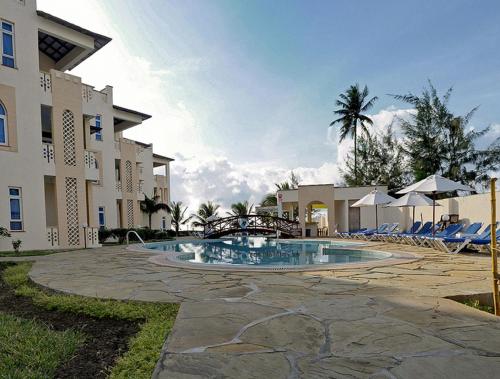 a resort with a pool and chairs and a building at Azul Margarita Beach Resort in Bamburi