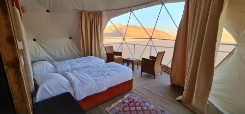 a bedroom with a bed and a large window at Hasan Zawaideh luxury camp 2 in Wadi Rum