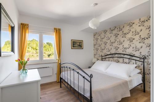 ein Schlafzimmer mit einem Bett und einem Fenster in der Unterkunft Villa Sinodium in Umljanović