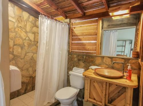 a bathroom with a toilet and a sink and a mirror at Hotel Restaurante Spa La Barca de Oro in Las Peñitas