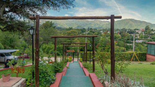 a garden with a green pathway with a pergola at Castelar - Hotel & Apart in Huerta Grande