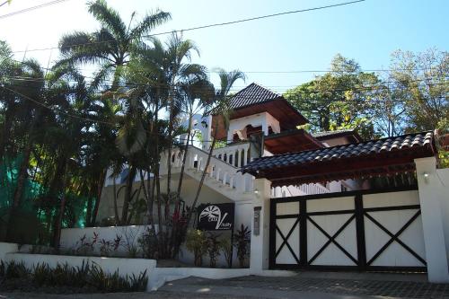 a white house with a gate and a palm tree at Casa Vitality Nosara in Nosara