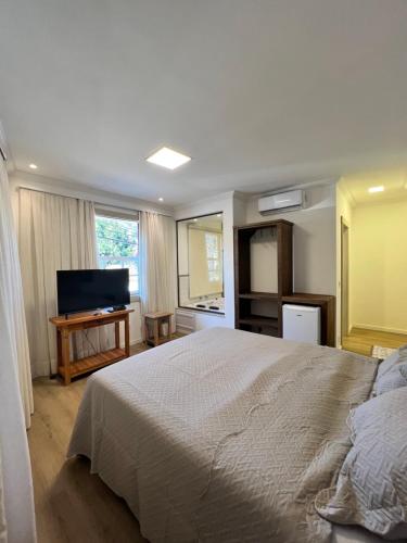 a bedroom with a bed and a flat screen tv at Pousada Tiradentes in Tiradentes