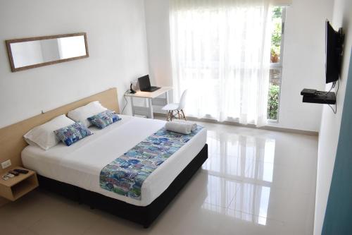 a white bedroom with a bed and a television at Color House Santa Marta in Santa Marta