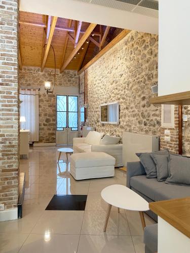 a living room with white furniture and a brick wall at Blue Domino Luxury City Villa Patras in Patra