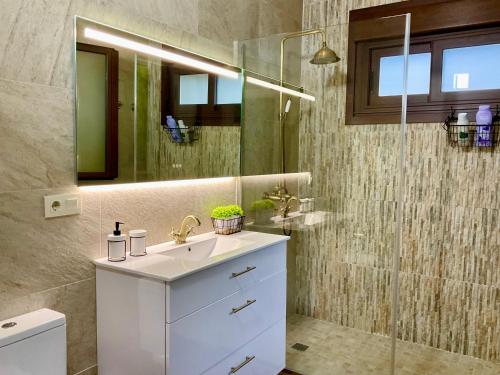La salle de bains est pourvue d'un lavabo et d'une douche en verre. dans l'établissement Casa Nueva de Vigo con Jacuzzi y chimenea, à Mos