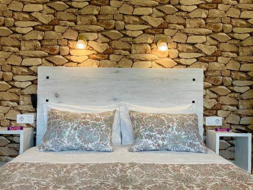a bed with two pillows in front of a stone wall at Casa nueva en Vigo Rural Mos con Jacuzzi y chimenea in Pontevedra