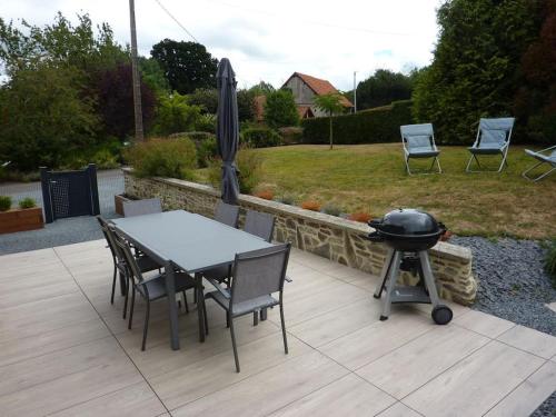 a table and chairs and a grill on a patio at Maison rénovée dans le bocage Normand avec jacuzzi in Canisy