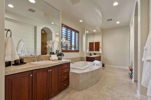 a bathroom with two sinks and a tub and a large mirror at Escape to Legends - Pool, Games & Amazing Mountain Views in PGA West #067651 5br in La Quinta