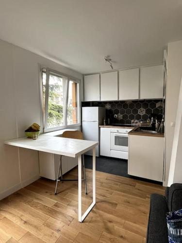 - une cuisine avec une table blanche dans une pièce dans l'établissement Appartement de standing calme - Paris - Métro 9, à Montreuil