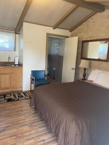 a bedroom with a bed and a bathroom with a sink at Woodland Motor Lodge in Grayling