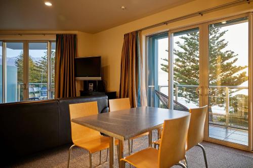 a dining room with a table and chairs and a balcony at Waves on the Esplanade in Kaikoura