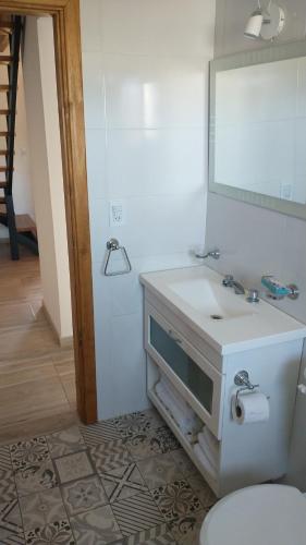 een badkamer met een witte wastafel en een spiegel bij Duplex familiar con pileta en zona parque in Necochea