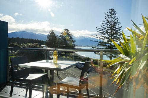 a table and chairs on a balcony with a view of the mountains at Waves on the Esplanade in Kaikoura