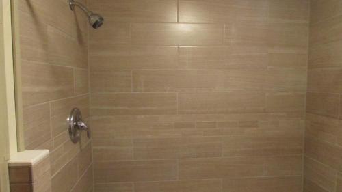 a bathroom with a shower with tan tile at Woodland Motor Lodge in Grayling