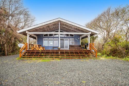a small blue house with a porch and benches at Ara Vista in Rockaway Beach