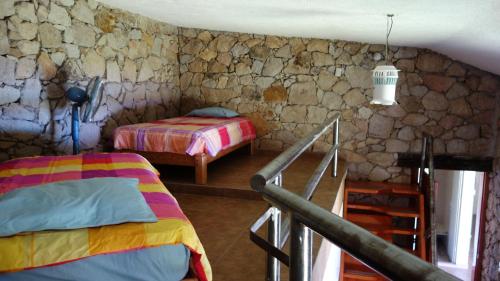 a bedroom with two beds and a stone wall at Casa de Piedra. Tequesquitengo in Tequesquitengo