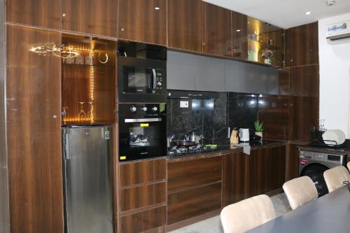 a kitchen with wooden cabinets and a stainless steel refrigerator at Excellent 2 bed apartment in Lekki Phase1 With SuperFast Wi-fi & 247 Power in Lekki