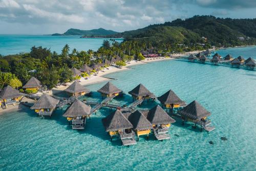 a beach area with umbrellas and boats at InterContinental Bora Bora Le Moana Resort, an IHG Hotel in Bora Bora