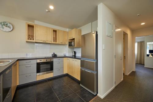 a kitchen with wooden cabinets and stainless steel appliances at Waves on the Esplanade in Kaikoura