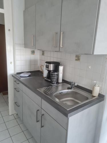 um balcão de cozinha com um lavatório e comodidades para preparar café em Ferienwohnung ADARO em Schleswig