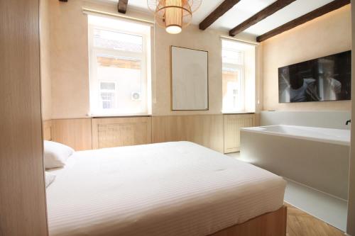 a bedroom with a white bed and a bath tub at Beige Apartment in Sarajevo