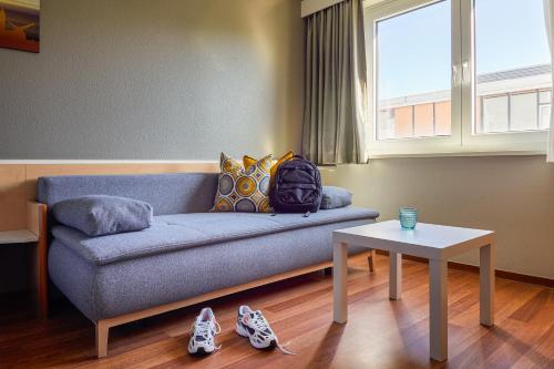 a living room with a blue couch and a table at ibis Hotel Würzburg City in Würzburg