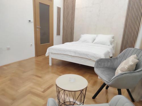 um quarto com uma cama, uma cadeira e uma mesa em Studio Apartman Lukavica em Sarajevo