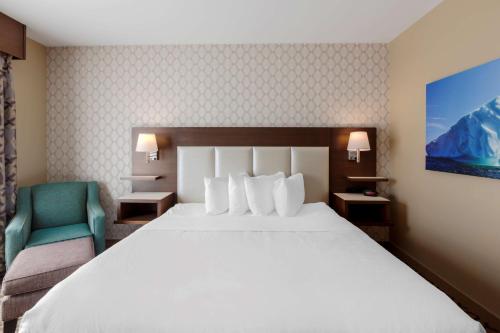 a hotel room with a large bed and a green chair at Best Western Plus St. John's Airport Hotel and Suites in St. John's