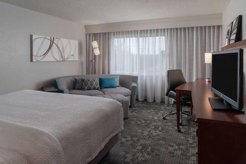 a hotel room with a bed and a couch and a television at Sonesta Select Chattanooga Hamilton Place in Chattanooga