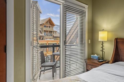 a bedroom with a window with a view of a balcony at Sophisticated MTN 2 Bedroom Pool Hot Tub managed by Little Sister Getaways in Canmore