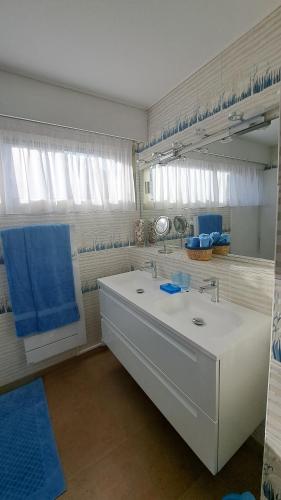 La salle de bains est pourvue d'un grand lavabo blanc et de serviettes bleues. dans l'établissement sylphides mg, à Antibes