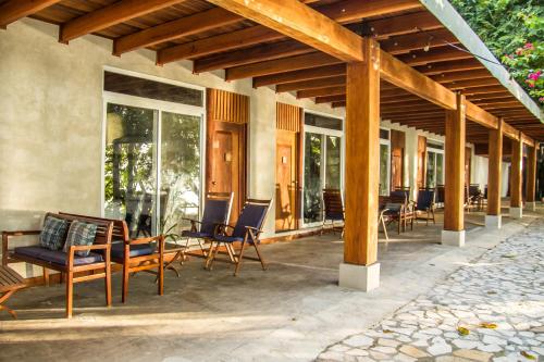 a patio with chairs and tables and windows at Hotel Gringo Perdido in El Remate