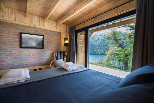 a bedroom with a bed with a large window at Hermoso Eco Lodge in San Martín de los Andes