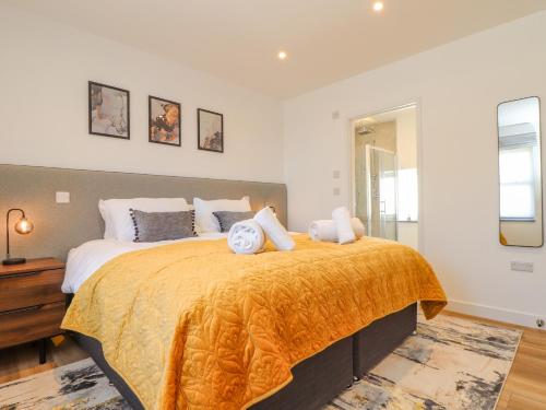een slaapkamer met een groot bed en een oranje deken bij Bal An Mor in Penzance