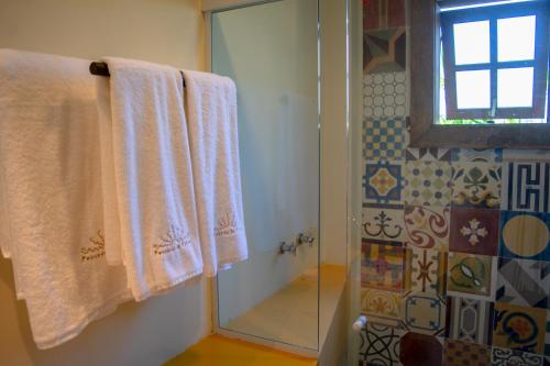 a bathroom with white towels and a shower at Pousada da Cyssa in Búzios