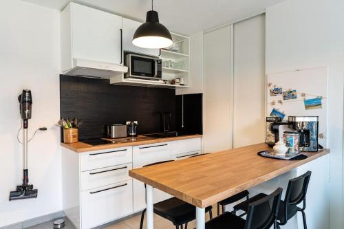 une cuisine avec des armoires blanches et une table en bois dans l'établissement Appartement cosy, à Biscarrosse
