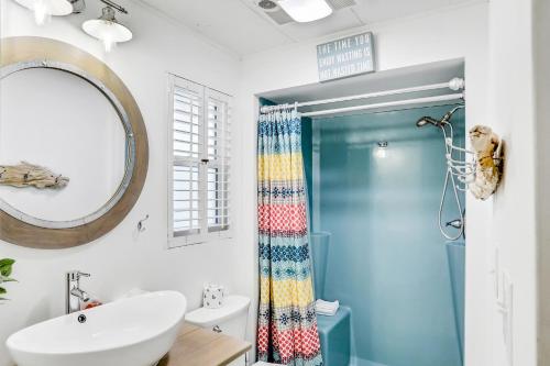 a bathroom with a sink and a mirror and a shower at Vilano Beach Oasis Bungalow in St. Augustine